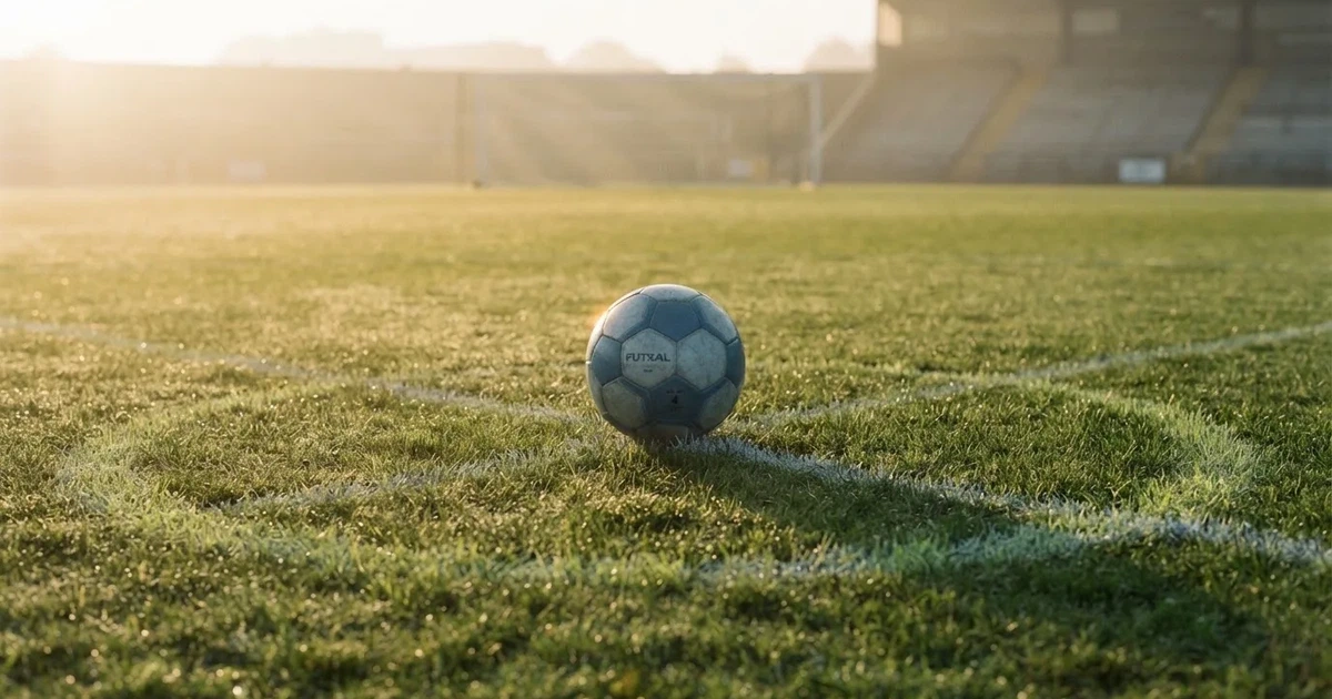 A ball on the centre spot of a grass pitch in morning light