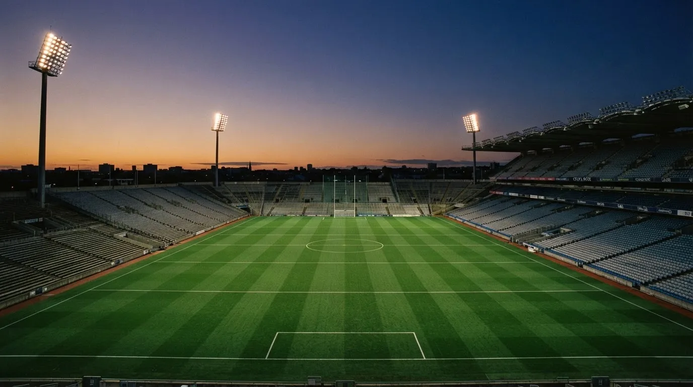 An empty football stadium with floodlight masts at dusk