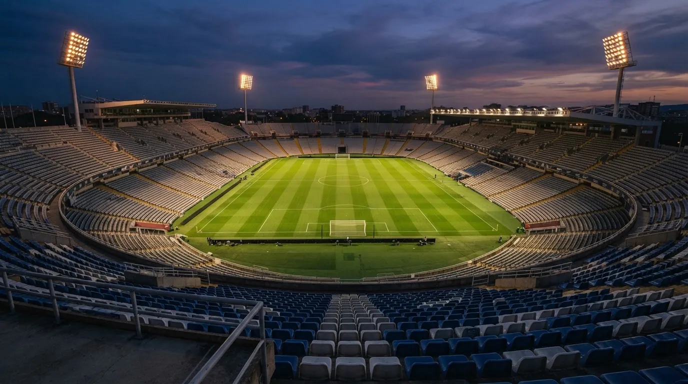 An empty football stadium with floodlight masts at dusk