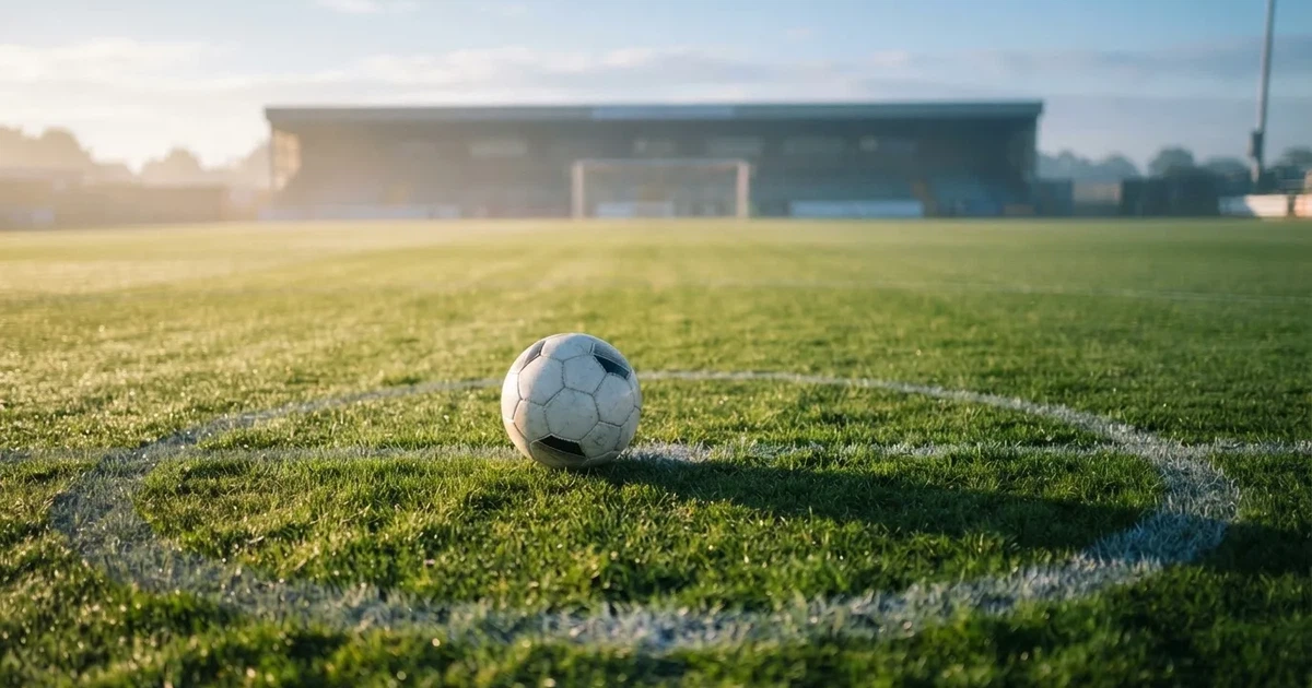 A ball on the centre spot of a grass pitch in morning light
