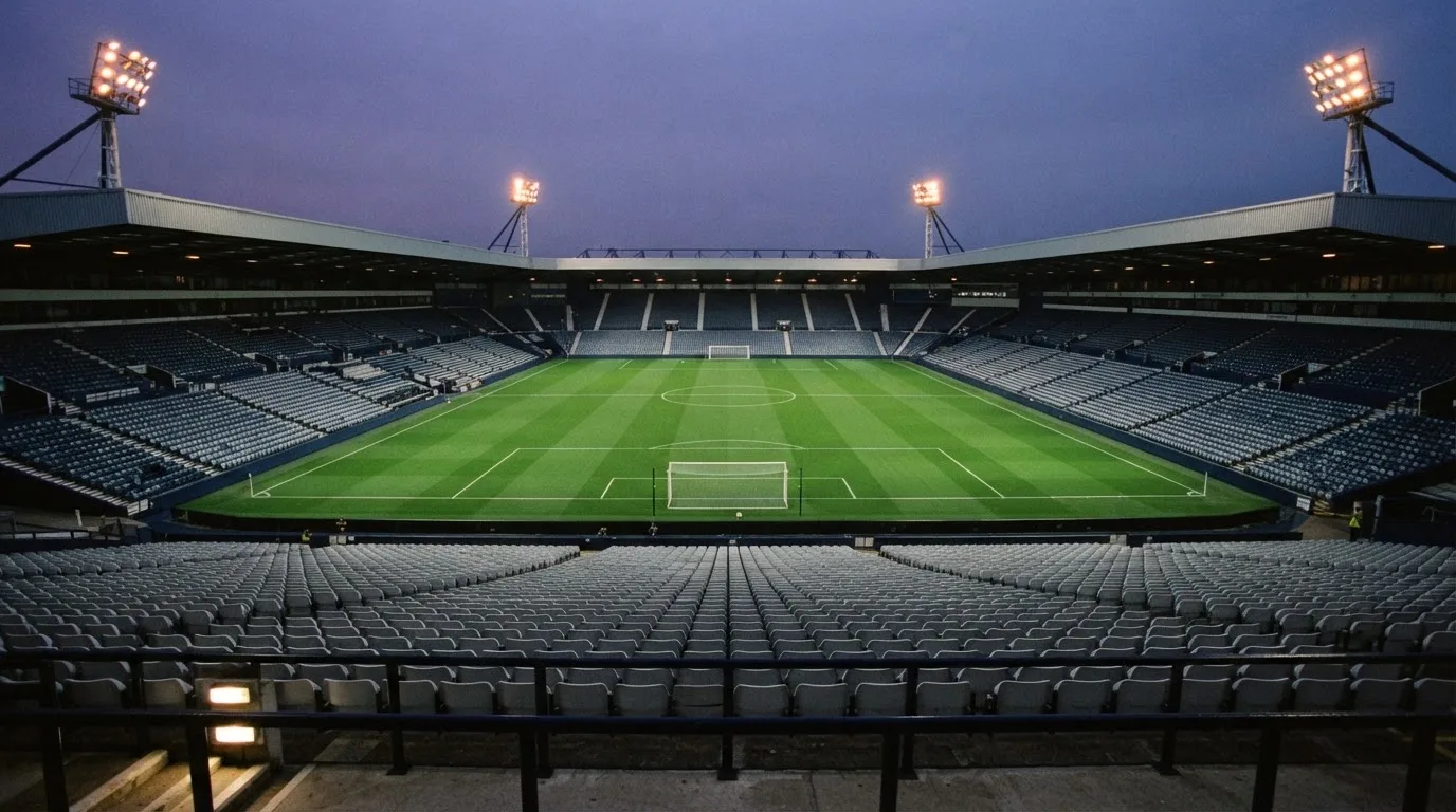 An empty football stadium with floodlight masts at dusk