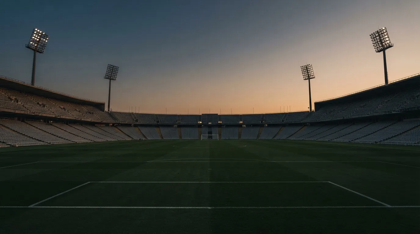An empty football stadium with floodlight masts at dusk