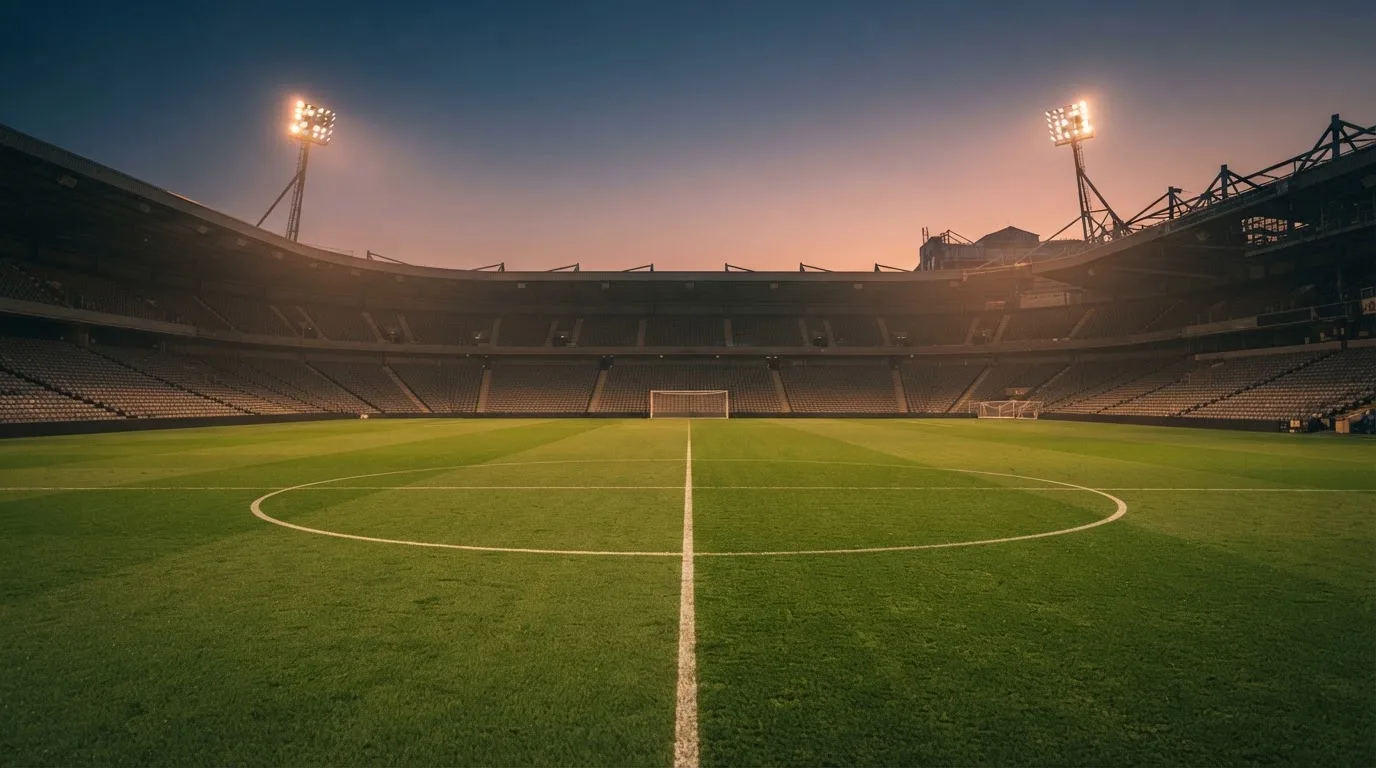 An empty football stadium with floodlight masts at dusk