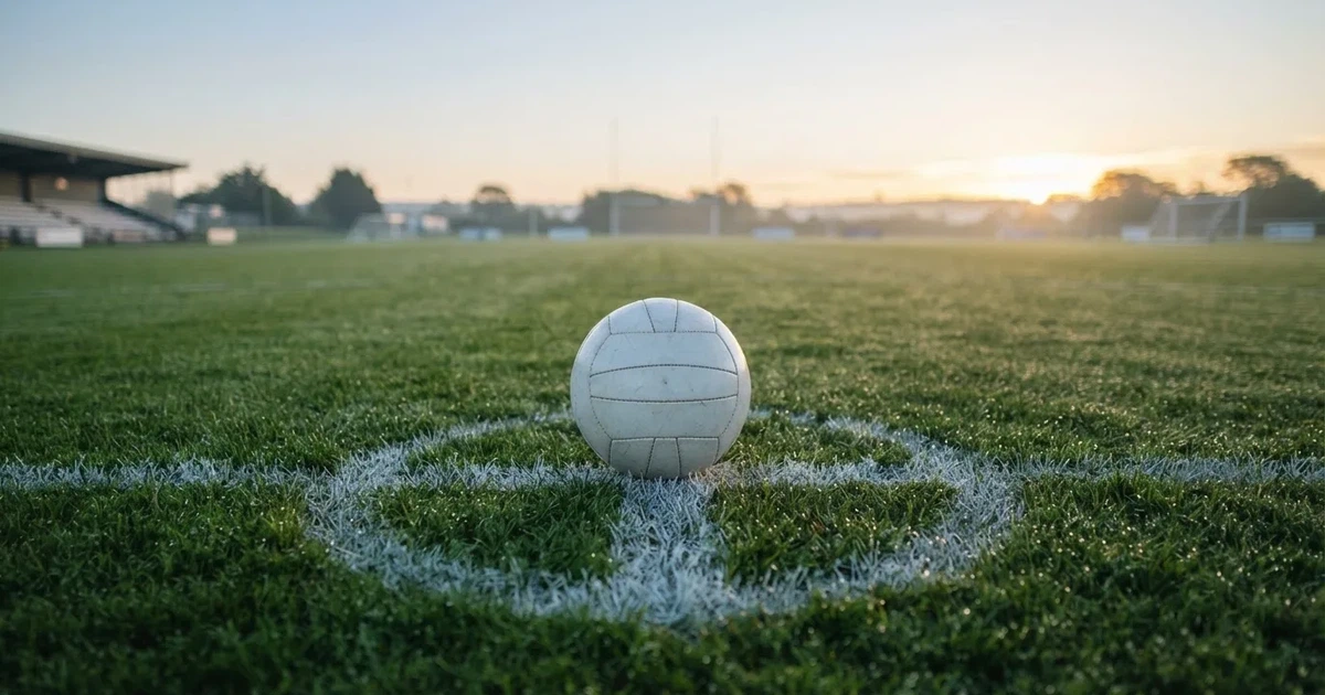 A ball on the centre spot of a grass pitch in morning light