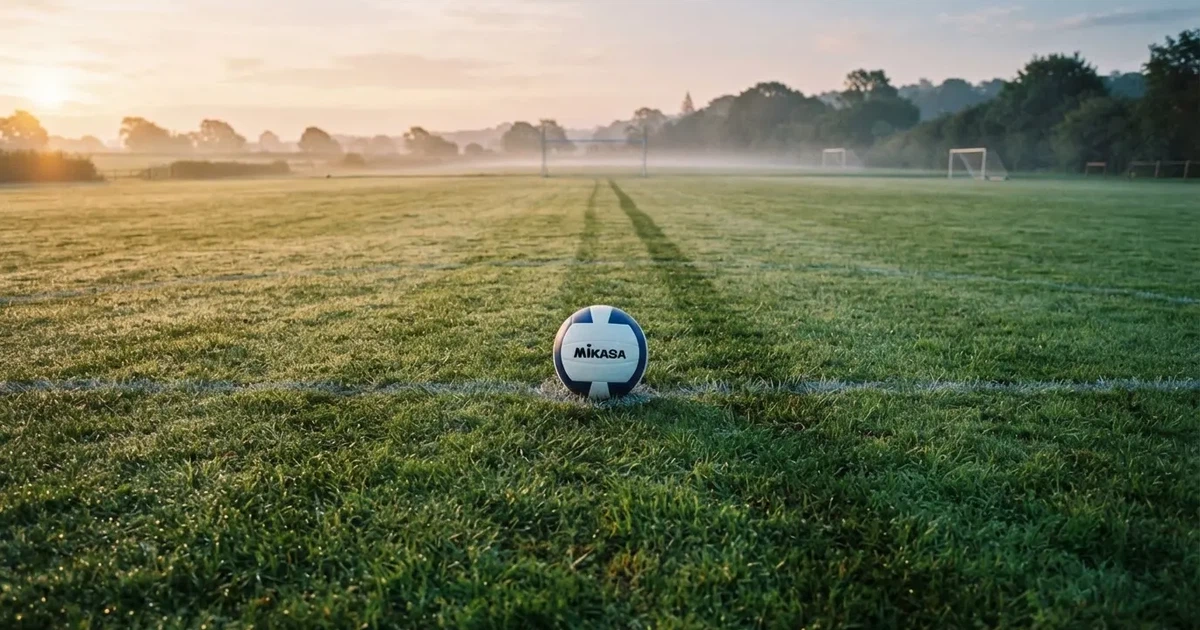 A ball on the centre spot of a grass pitch in morning light