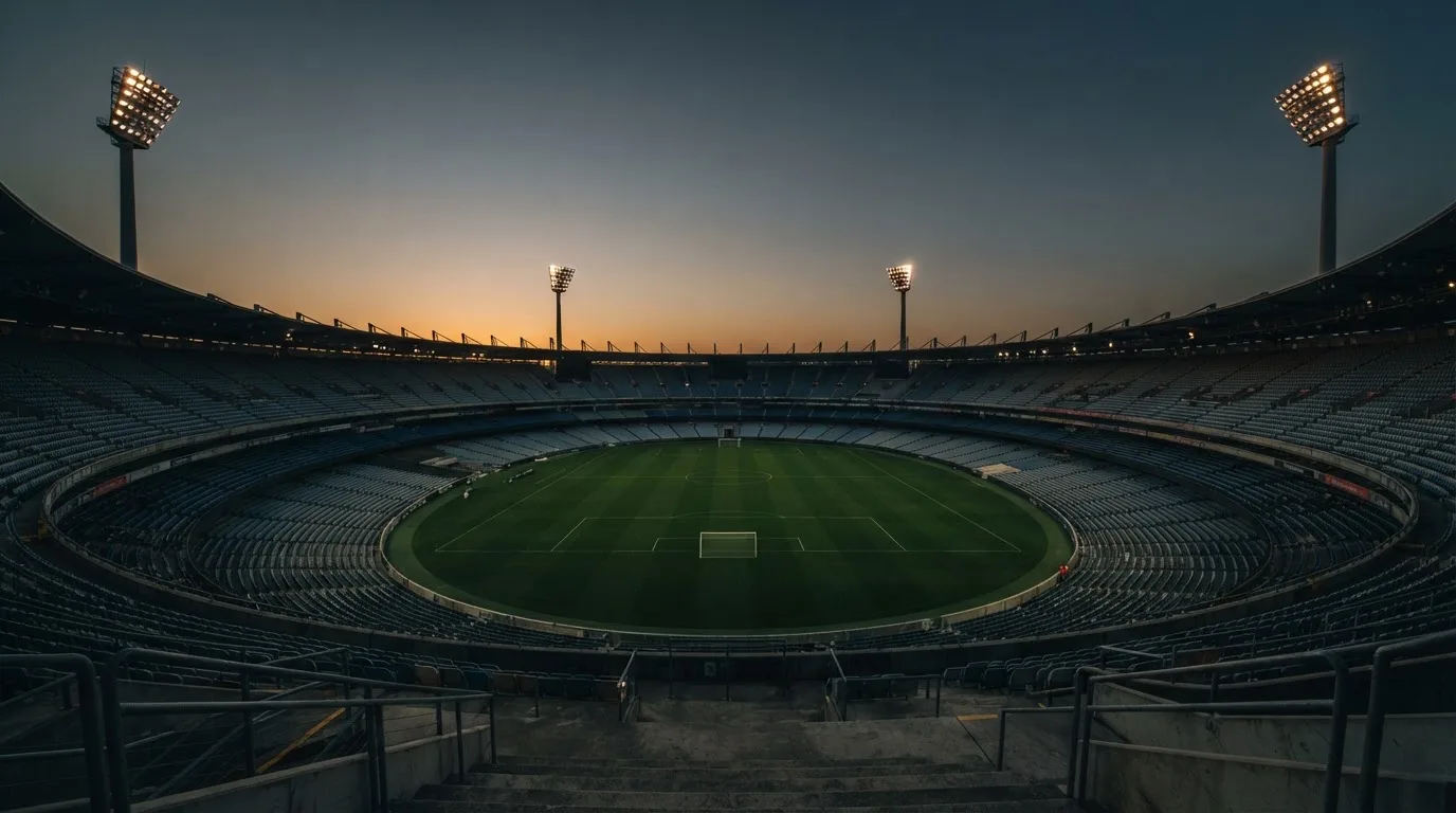 An empty football stadium with floodlight masts at dusk