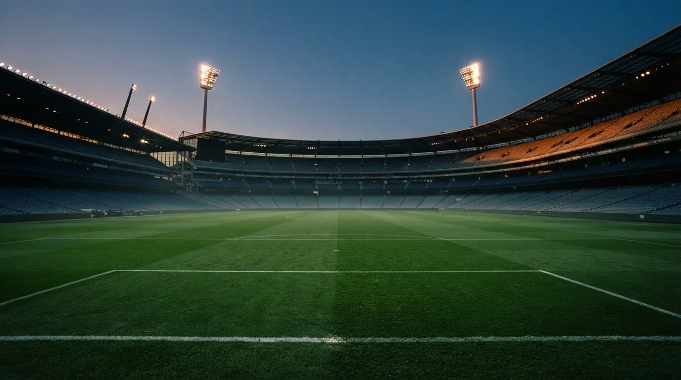 An empty football stadium with floodlight masts at dusk