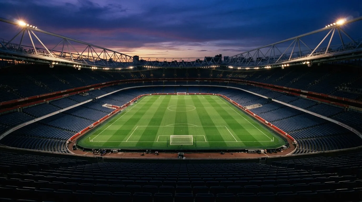 An empty football stadium with floodlight masts at dusk